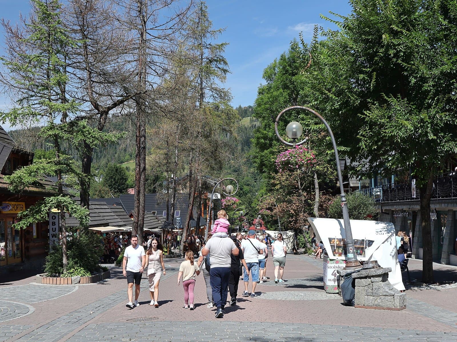 Rua Krupówki cheia de gente, com montanhas ao fundo